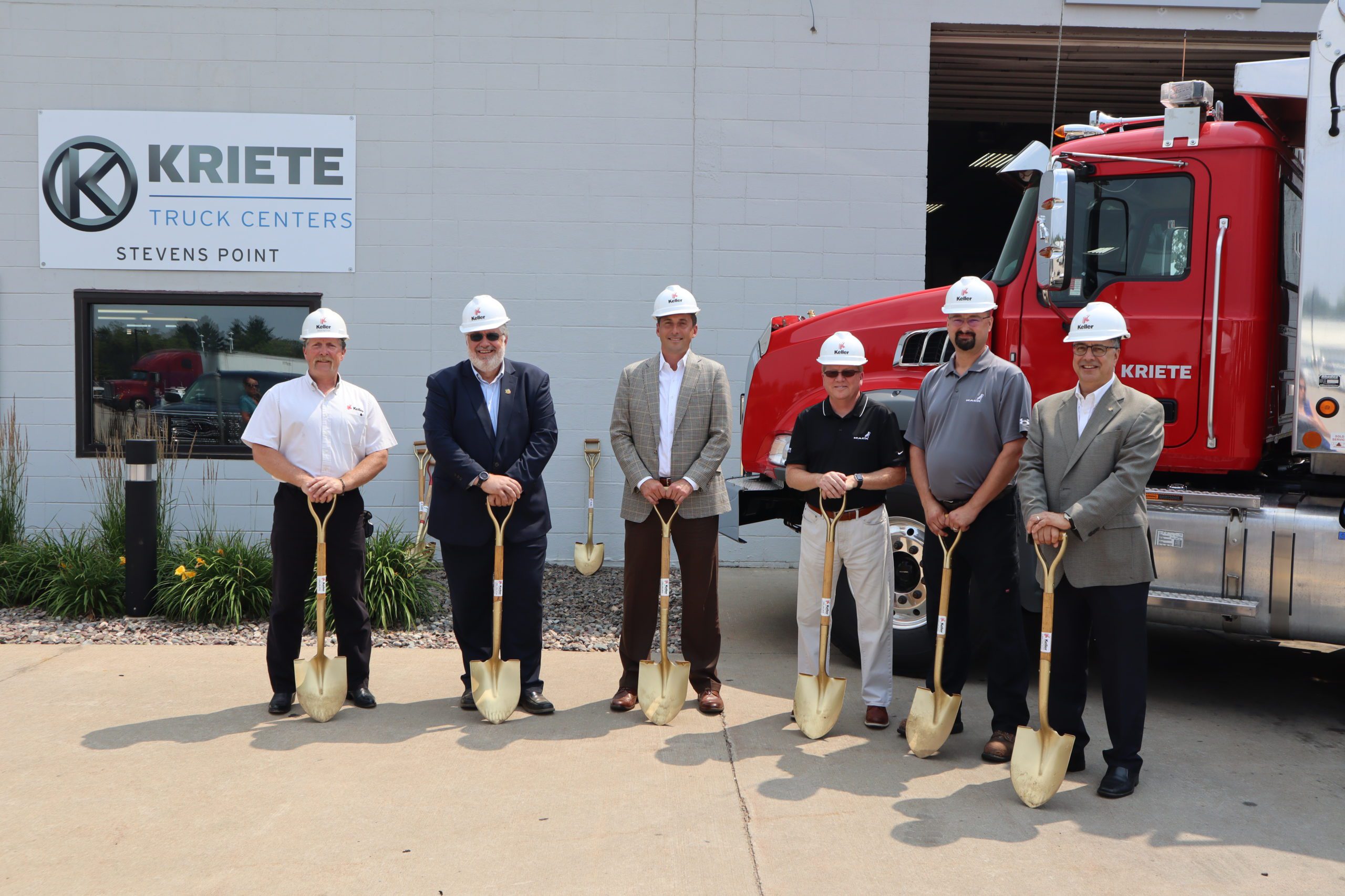 Construction team holding gold shovels at groundbreaking for Kriete Truck Centers project