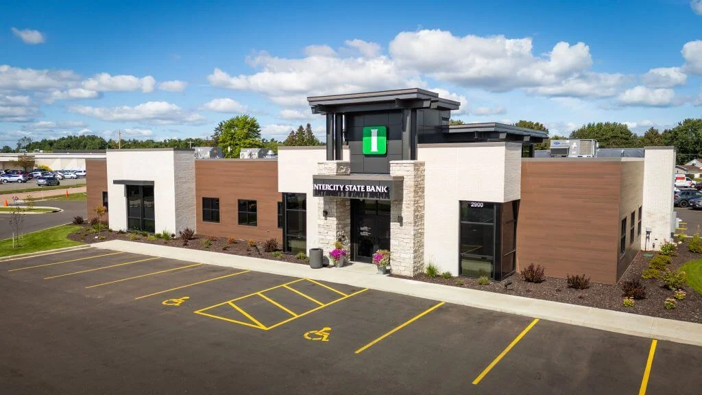 Modern exterior of Intercity State Bank featuring a stone and wood facade, clear signage, and well-maintained landscaping, situated in a spacious parking lot with designated accessibility spaces.