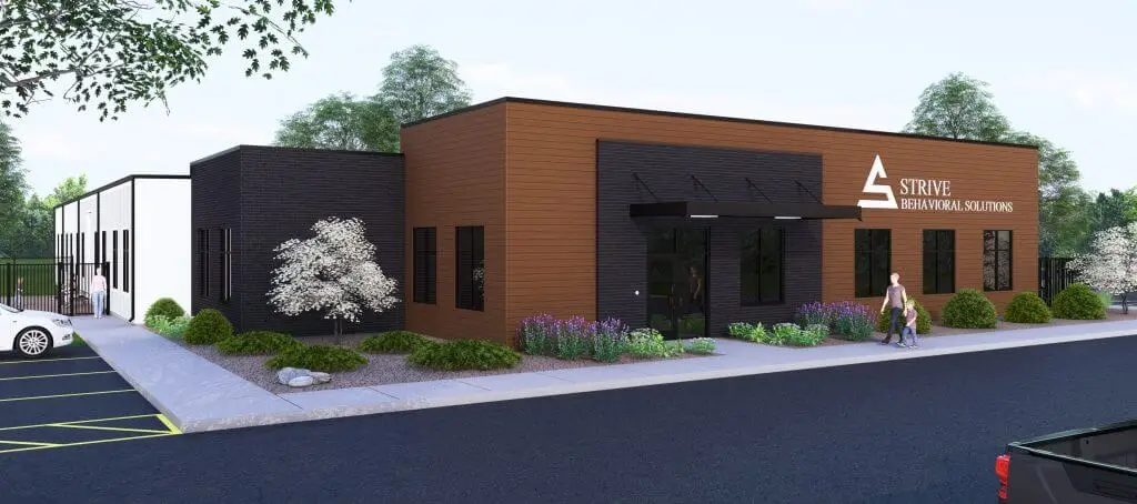 Exterior view of Strive Behavioral Solutions building featuring modern architecture, greenery, and a welcoming entrance with pedestrians. The facility emphasizes mental health services in a serene environment.